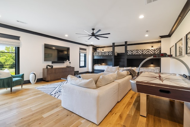 living room with ceiling fan, ornamental molding, and light wood-type flooring