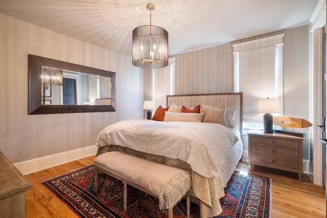 bedroom with light hardwood / wood-style flooring and an inviting chandelier