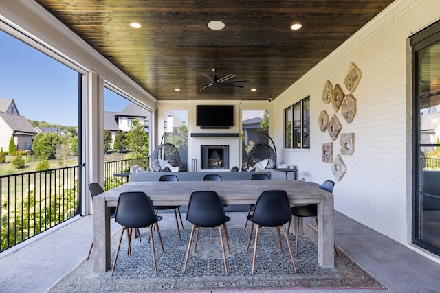 sunroom / solarium with an outdoor fireplace, ceiling fan, and wooden ceiling