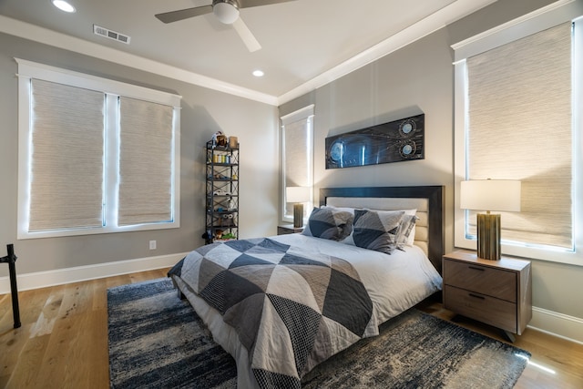 bedroom featuring ornamental molding, multiple windows, light wood-type flooring, and ceiling fan