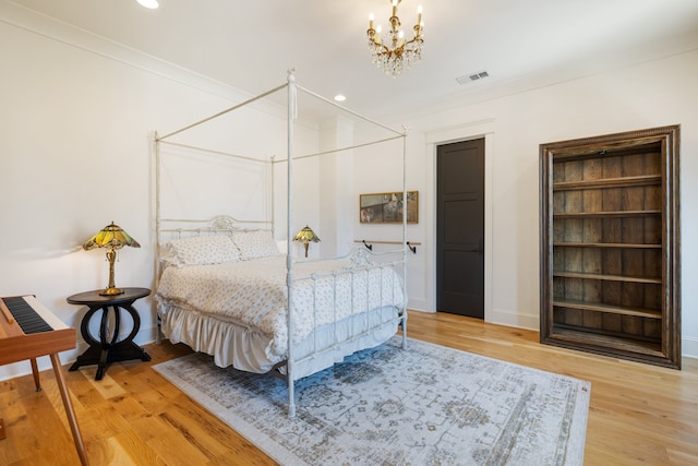 bedroom featuring ornamental molding, hardwood / wood-style flooring, and a chandelier