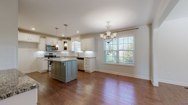 kitchen featuring white cabinets, light stone countertops, stainless steel appliances, decorative light fixtures, and a center island