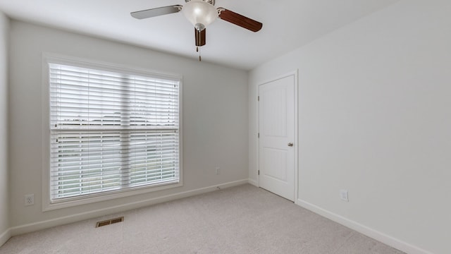 carpeted spare room with ceiling fan and plenty of natural light