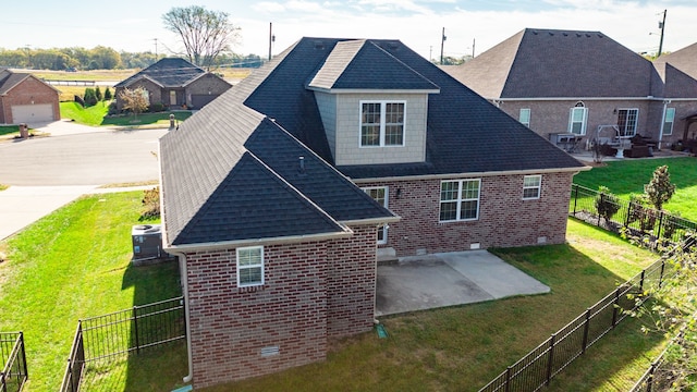 rear view of house featuring a patio area, a garage, and a lawn