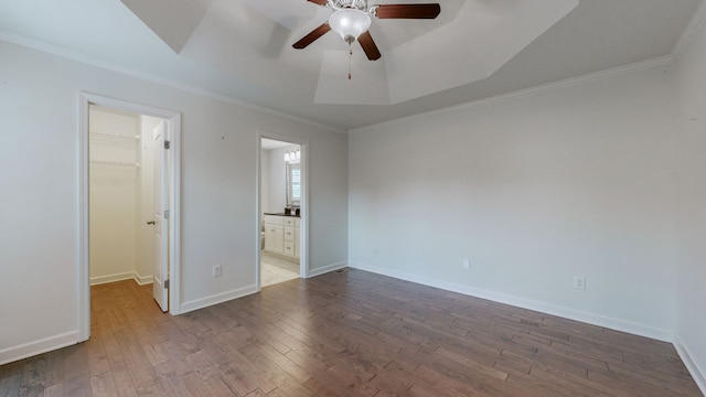 unfurnished bedroom with a closet, a spacious closet, ornamental molding, hardwood / wood-style floors, and ceiling fan