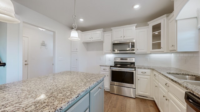 kitchen with appliances with stainless steel finishes, white cabinetry, dark wood-type flooring, and pendant lighting