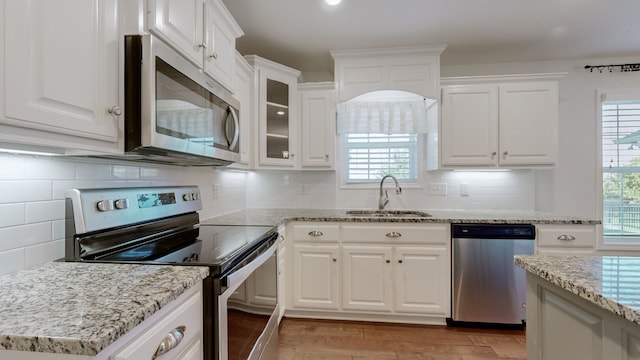 kitchen with decorative backsplash, white cabinets, stainless steel appliances, and sink