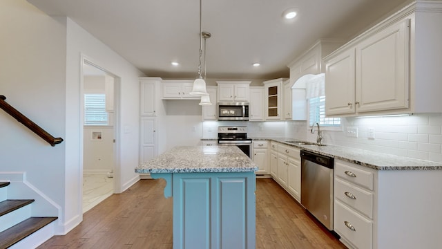 kitchen featuring appliances with stainless steel finishes, a center island, sink, and light wood-type flooring