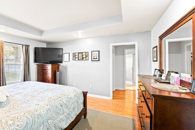 bedroom featuring light hardwood / wood-style flooring and a raised ceiling