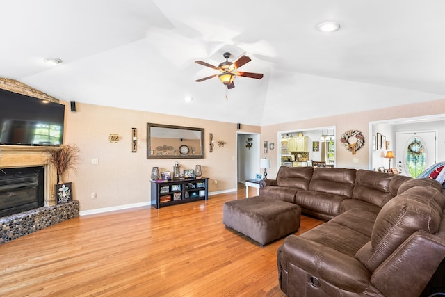 living room with a large fireplace, vaulted ceiling, light wood-type flooring, and ceiling fan