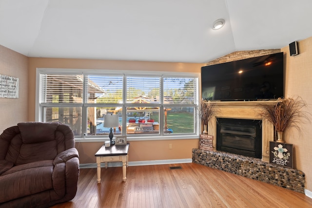 living room featuring a large fireplace, wood-type flooring, and lofted ceiling