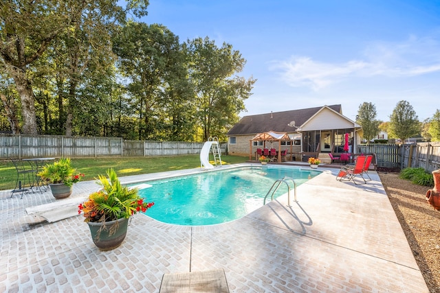 view of swimming pool featuring a water slide, a diving board, and a patio