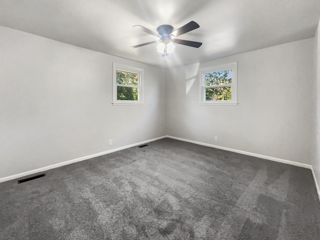 carpeted spare room featuring ceiling fan and a wealth of natural light