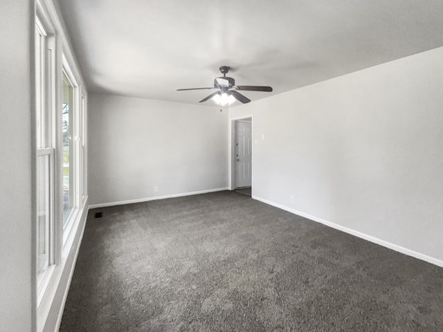 spare room featuring ceiling fan and dark carpet