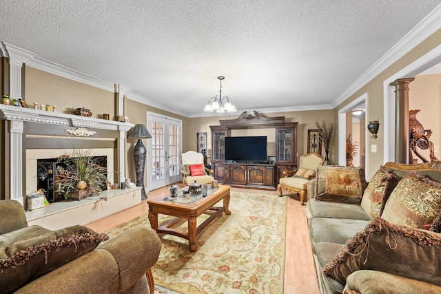 living room featuring ornate columns, crown molding, a chandelier, a textured ceiling, and light hardwood / wood-style floors