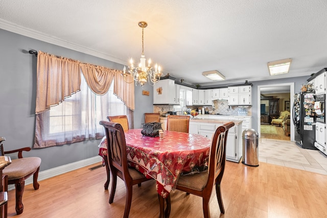 dining room featuring crown molding, a notable chandelier, a textured ceiling, and light hardwood / wood-style flooring