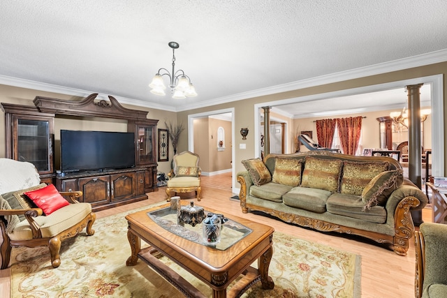 living room with ornamental molding, a chandelier, light hardwood / wood-style flooring, and decorative columns