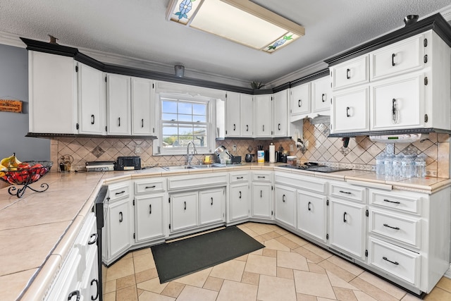 kitchen featuring white cabinets, black gas cooktop, a textured ceiling, crown molding, and sink