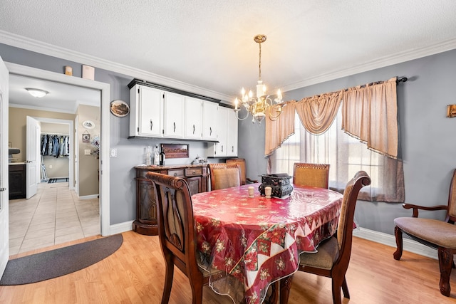 dining space with light hardwood / wood-style floors, ornamental molding, a chandelier, and a textured ceiling