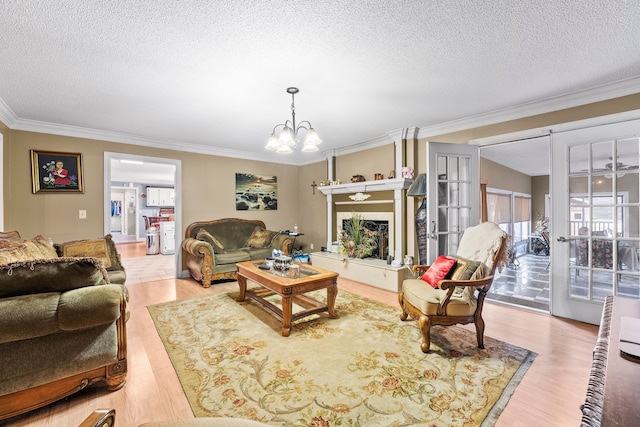 living room featuring an inviting chandelier, a textured ceiling, a fireplace, light hardwood / wood-style floors, and crown molding