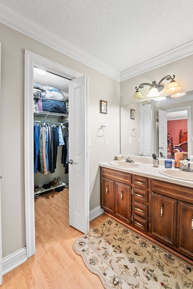 bathroom featuring vanity, crown molding, a textured ceiling, and hardwood / wood-style floors