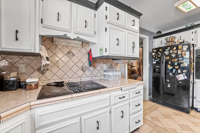 kitchen with white cabinets, a textured ceiling, light tile patterned flooring, black appliances, and crown molding