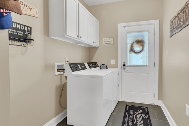 laundry room with washing machine and clothes dryer, cabinets, and dark tile patterned flooring