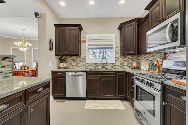 kitchen featuring backsplash, ornamental molding, sink, a notable chandelier, and stainless steel appliances