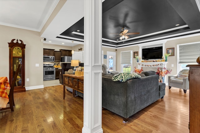 living room with ornamental molding, hardwood / wood-style floors, a healthy amount of sunlight, and a tray ceiling