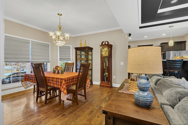 dining area with a notable chandelier, ornamental molding, and dark hardwood / wood-style flooring