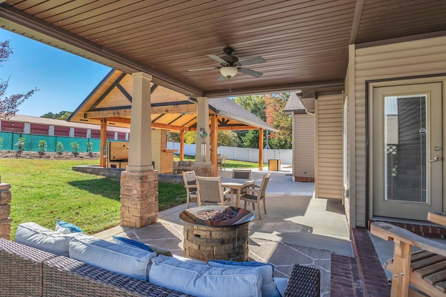 view of patio / terrace with a gazebo, ceiling fan, an outdoor living space with a fire pit, and a swimming pool