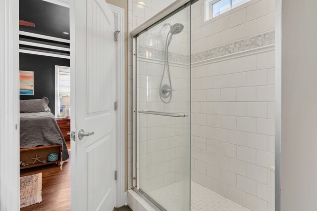 bathroom featuring a shower with shower door and wood-type flooring