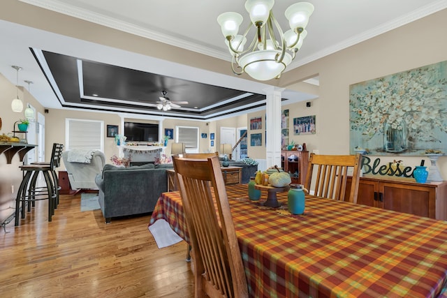 dining area featuring hardwood / wood-style flooring, ornamental molding, a tray ceiling, and ceiling fan with notable chandelier