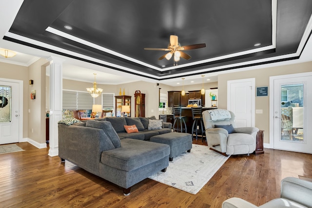 living room with dark hardwood / wood-style floors, ceiling fan with notable chandelier, and a raised ceiling