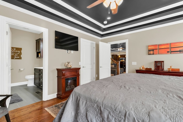 bedroom with ceiling fan, ornamental molding, ensuite bath, and hardwood / wood-style floors