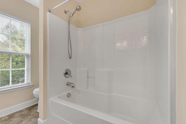 bathroom featuring toilet, a healthy amount of sunlight, and shower / tub combination