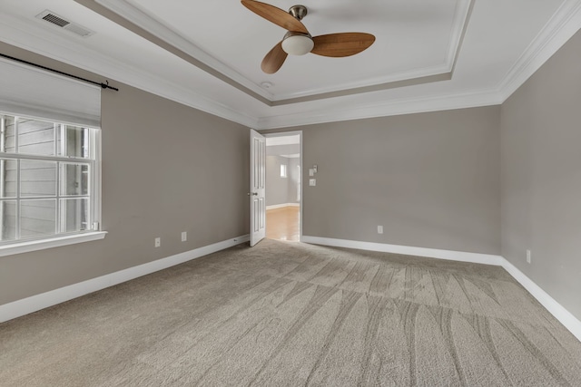 carpeted spare room featuring crown molding, a tray ceiling, and ceiling fan