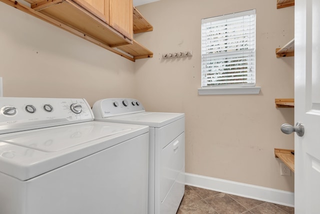 laundry area with dark tile patterned flooring, washing machine and dryer, and cabinets