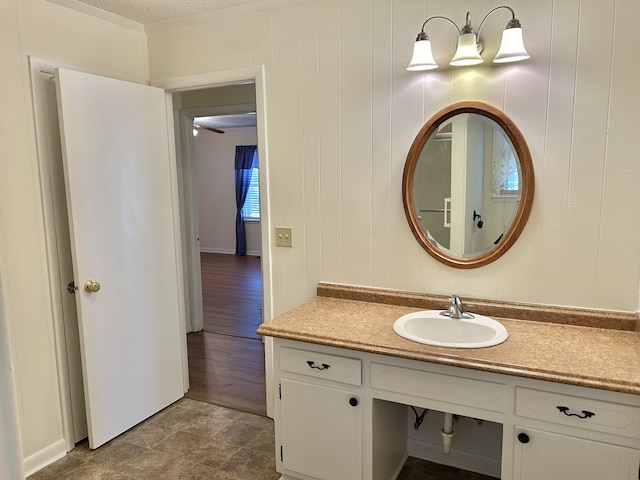 bathroom with vanity, hardwood / wood-style flooring, a textured ceiling, and wooden walls