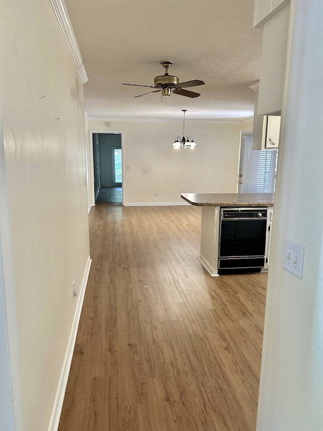 hallway featuring ornamental molding, a textured ceiling, and light wood-type flooring