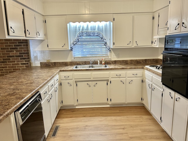 kitchen featuring sink, black appliances, and white cabinetry