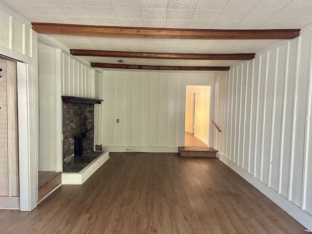 unfurnished living room featuring beamed ceiling, dark wood-type flooring, and wood walls