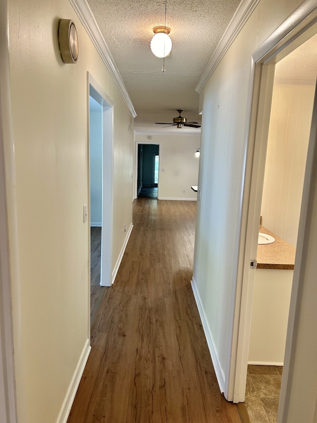 hallway with ornamental molding, a textured ceiling, and dark wood-type flooring