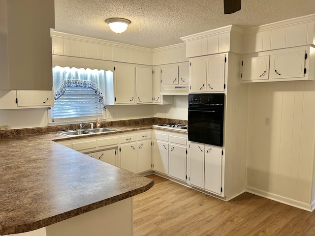 kitchen featuring light hardwood / wood-style floors, white cabinets, black oven, and sink