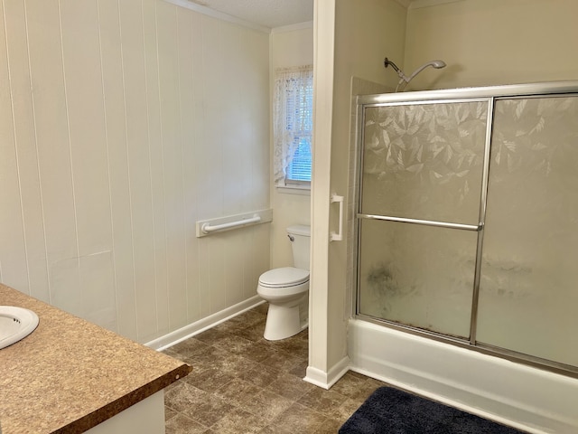 full bathroom featuring vanity, toilet, wooden walls, and bath / shower combo with glass door