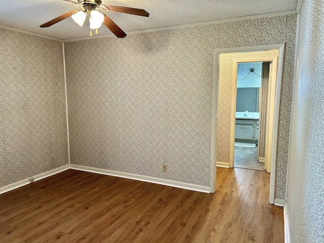 spare room with a textured ceiling, wood-type flooring, and ceiling fan