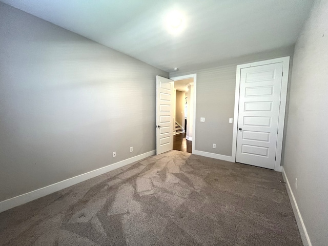 unfurnished bedroom with dark colored carpet and a closet