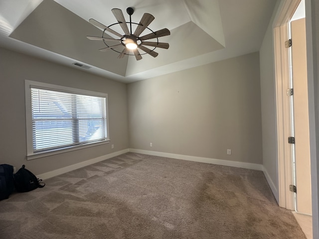 unfurnished room featuring carpet floors, a tray ceiling, and ceiling fan