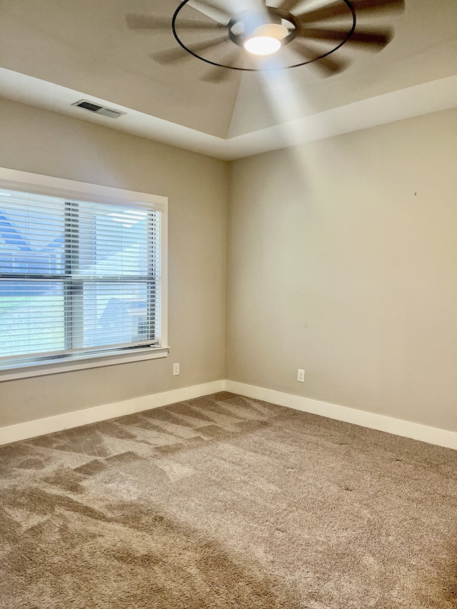 empty room featuring carpet flooring, a tray ceiling, and ceiling fan