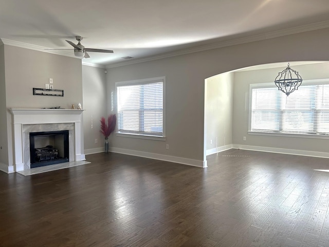 unfurnished living room featuring dark hardwood / wood-style flooring, ceiling fan with notable chandelier, and crown molding